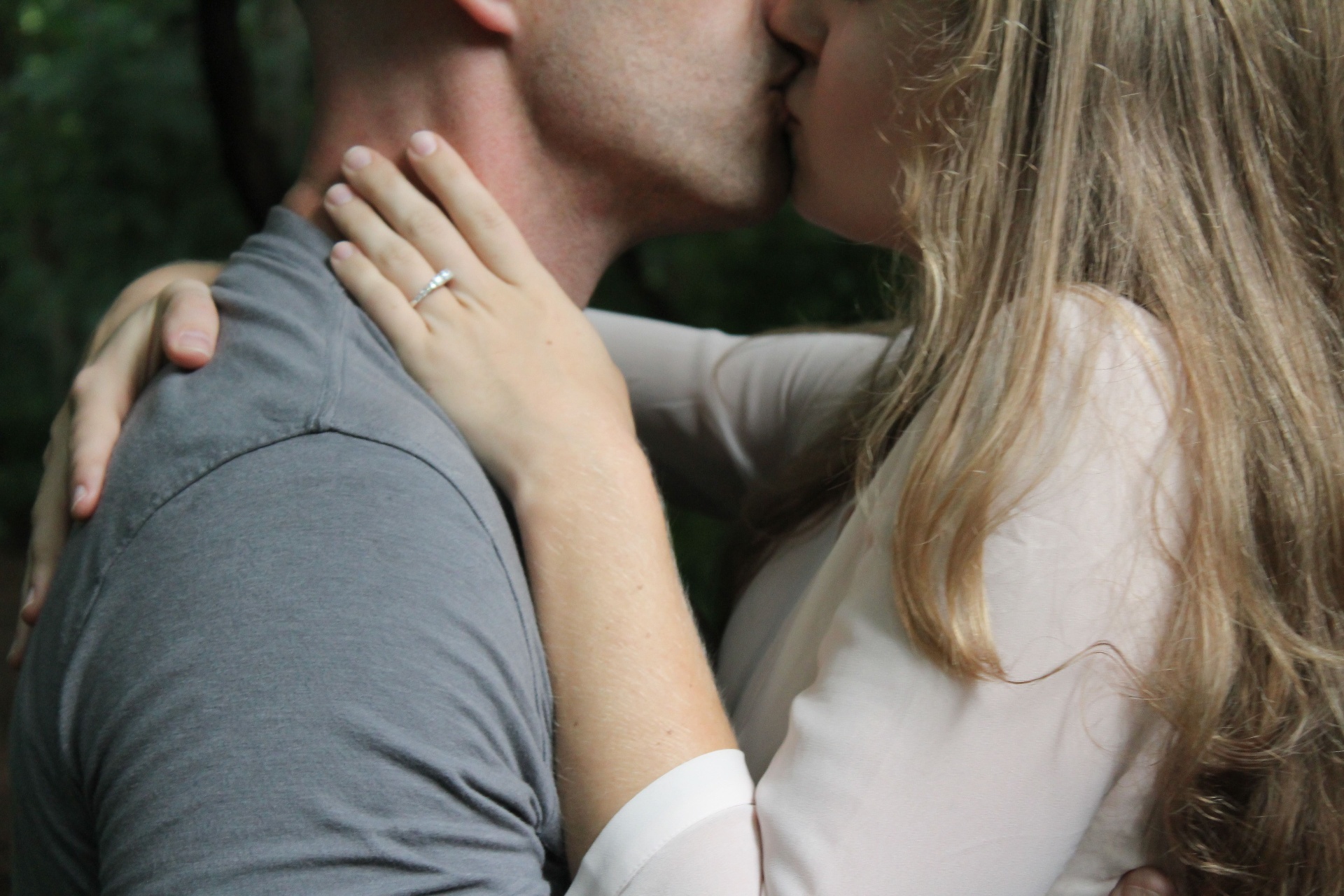 A couple in a close, tender kiss with a hand resting gently on the other's shoulder.