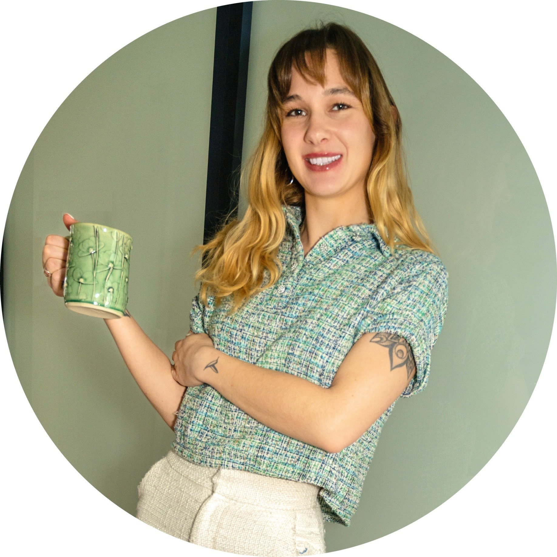 Haile smiling and holding a handmade green ceramic mug